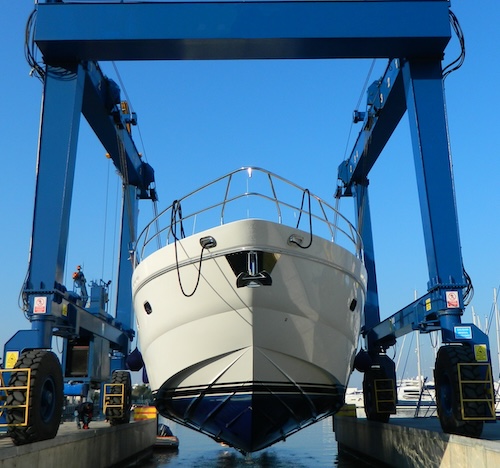 Luxury motor yacht lifted by a special crane for the annual repair, painting and inspection. Transportation industry. Car mechanic. Repair service. Luxury motor yacht lifted by a special crane for the annual repair, painting and inspection. Transportation industry. Car mechanic. Repair service.